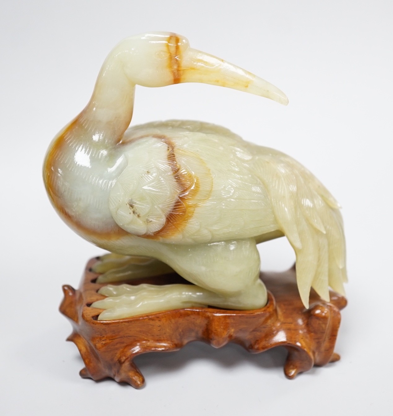 A Chinese green and russet jade figure of a crane, 11.5cm long, wood stand